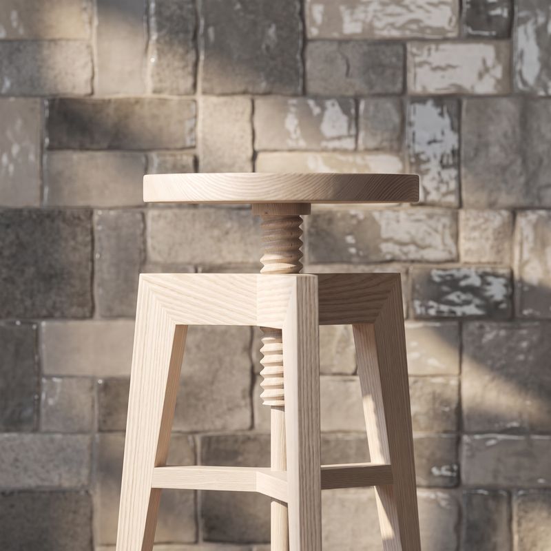 Heller Holzhocker mit gedrechselter Spindel vor einer rauen Steinmauer im Sonnenlicht