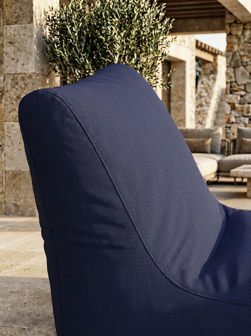 Nahaufnahme eines dunkelblauen Outdoor-Loungesessels vor einem Olivenbaum auf einer Steinterrasse