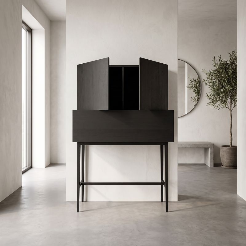 Hoher schwarzer Schrank mit zwei schräg geöffneten oberen Türen auf schlanken Metallbeinen, in einem minimalistischen Raum mit Olivenbaum und rundem Spiegel